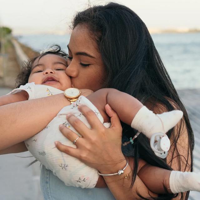 A woman holds and kisses her baby