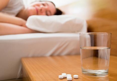 nightstand with melatonin tablets and a glass of water